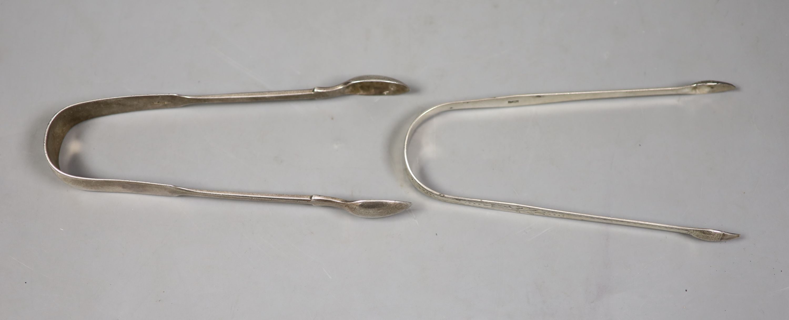 Two pairs of Georgina silver sugar tongs, one with bright cut engraving, largest 15.5cm, 83 grams.